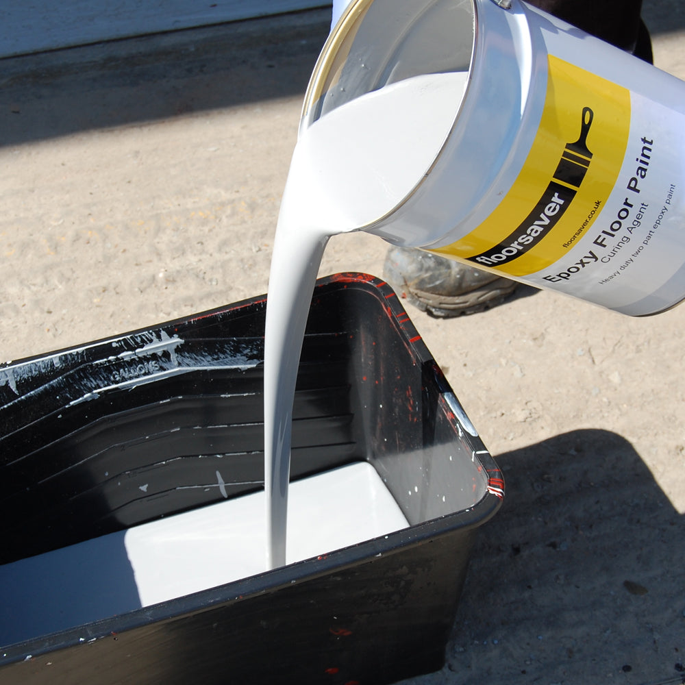 Versement de la Peinture Époxy Pour Sol dans un bac à peinture